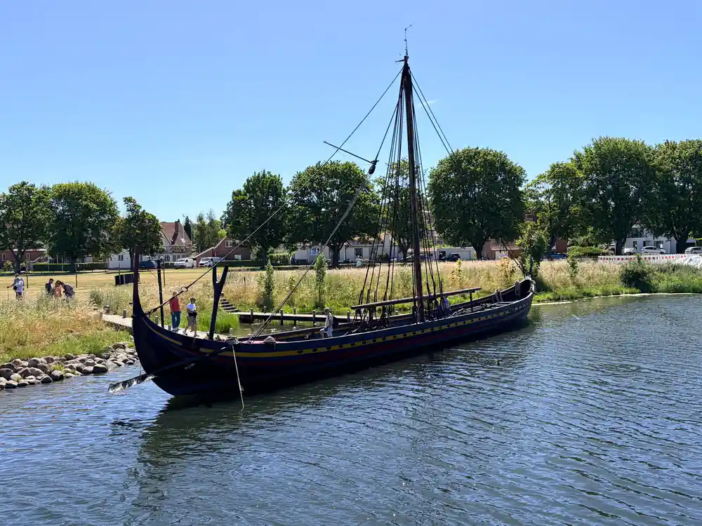 Black Viking longship replica moored by grassy bank