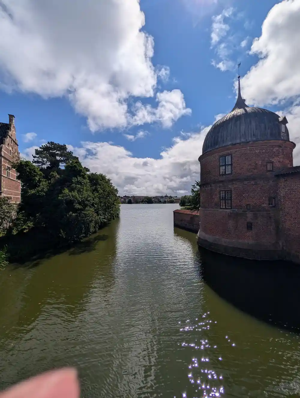 Brick tower reflected in still water under blue sky
