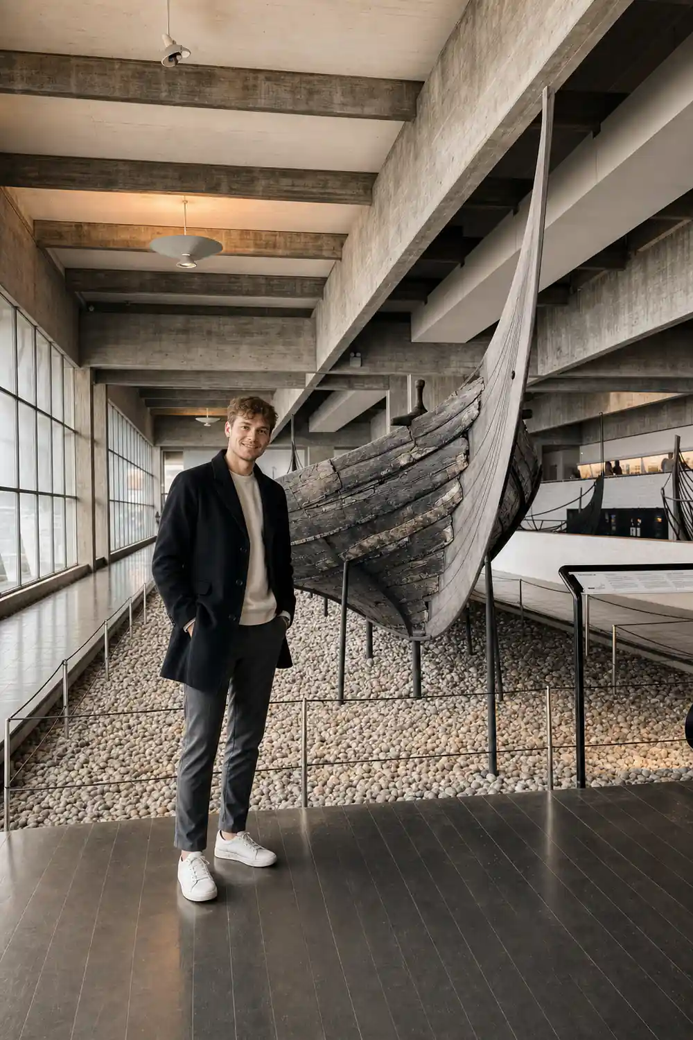 Man posing beside large wooden Viking ship hull indoors