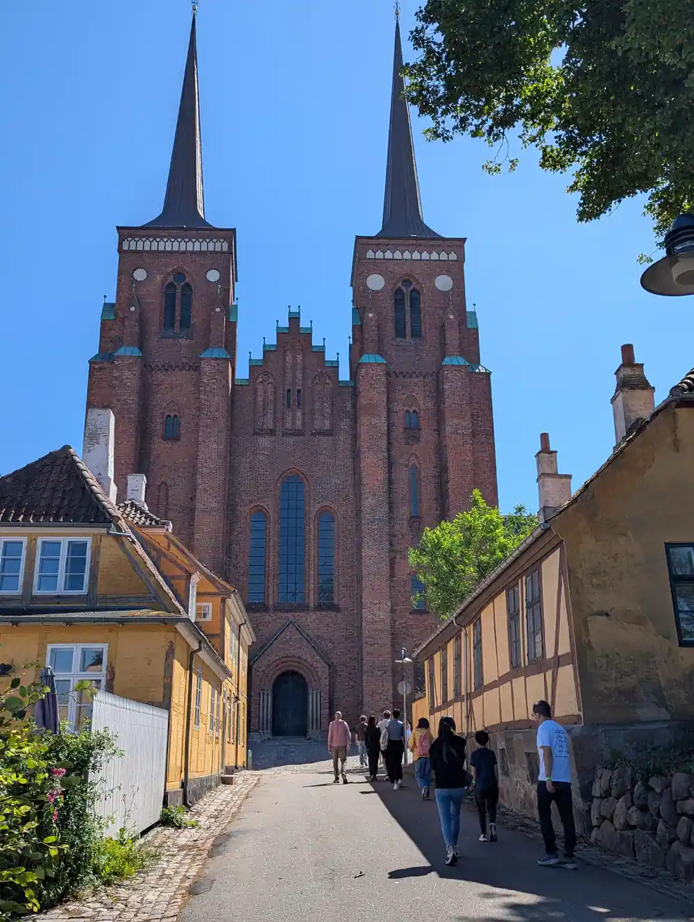 Red brick twin-spired church on cobbled street