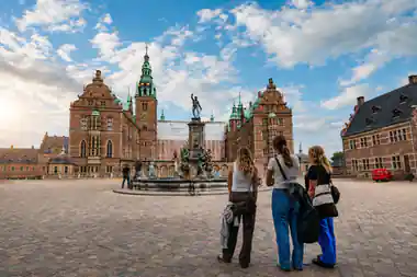 Tourists viewing statue in historic plaza with red-brick buildings