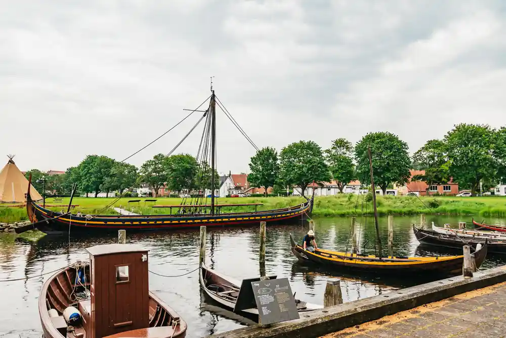 Traditional wooden boats moored in shallow water with green fields