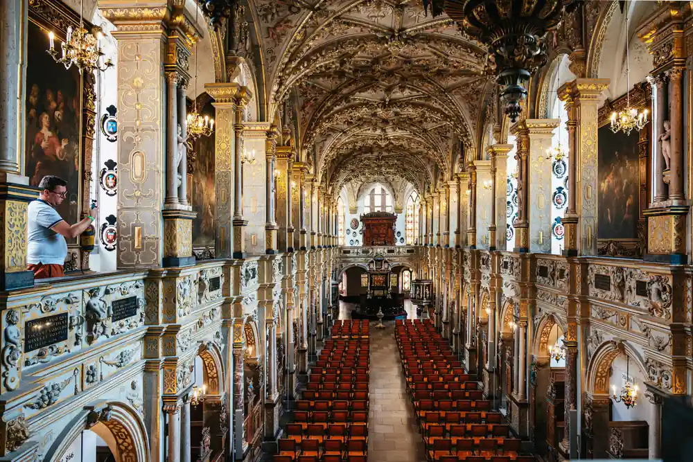 Woman walking through decorated palace hall with ornate ceiling